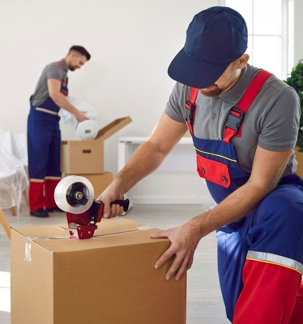 A Man Is Taping A Box With A Tape Dispenser — Port Stephens Removals & Storage In Raymond Terrace, NSW