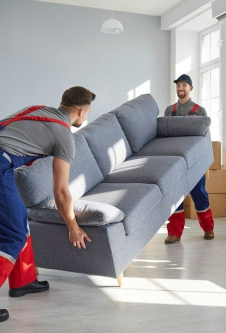 Two Men Are Carrying A Couch In A Living Room — Port Stephens Removals & Storage In Raymond Terrace, NSW