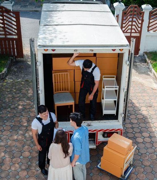 A Group Of People Standing In Front Of A Moving Truck — Port Stephens Removals & Storage In Williamtown, NSW