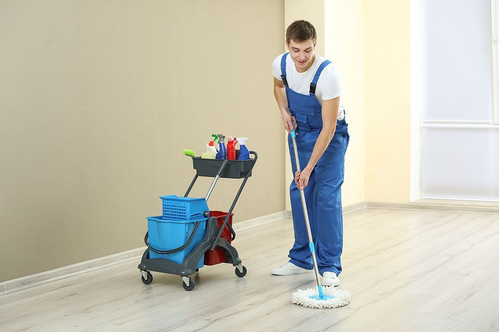A Man is Cleaning the Floor With a Mop in a Room  — Port Stephens Removals & Storage In Salt Ash, NSW