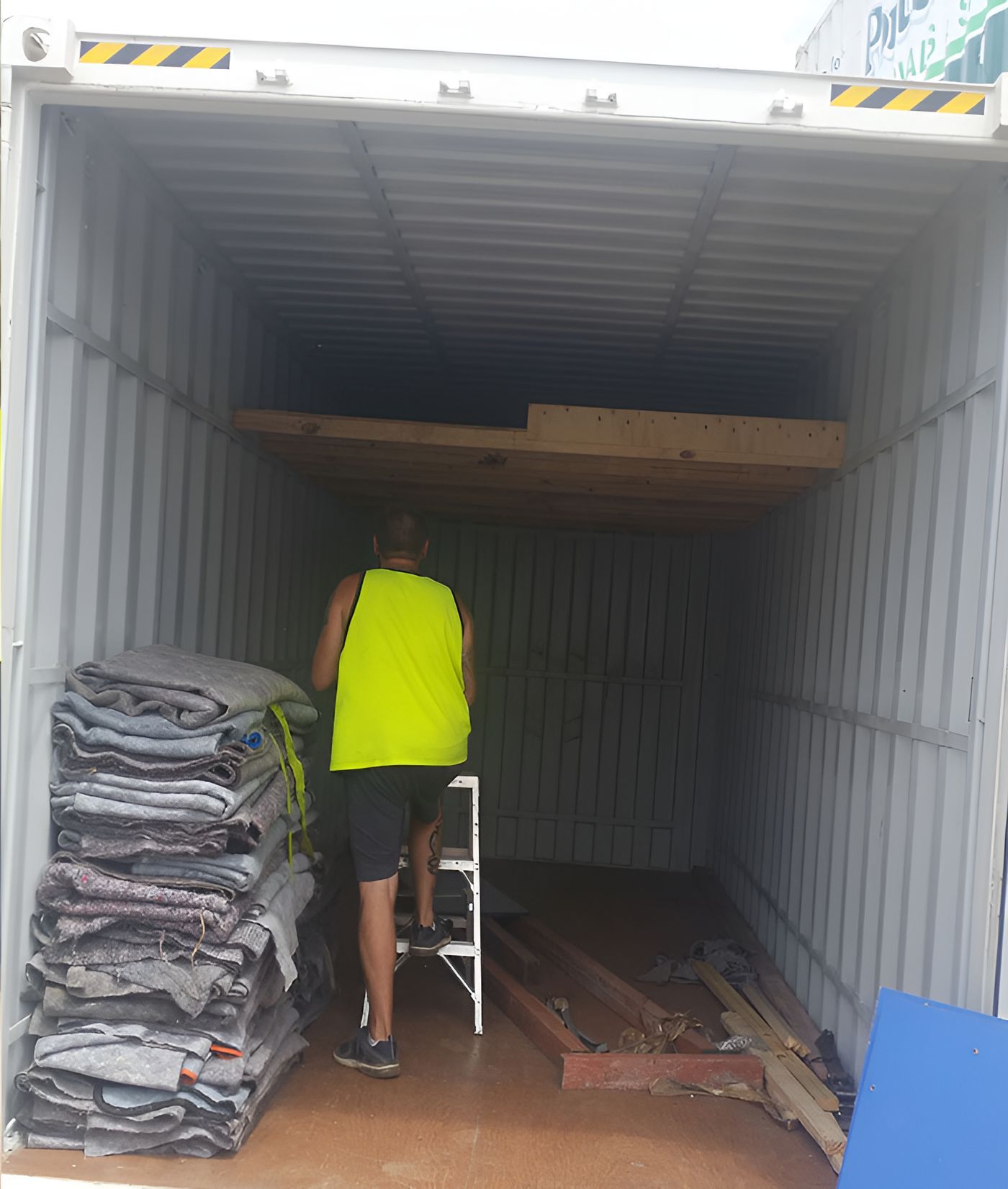 A Man In A Yellow Vest Is Standing In A Shipping Container — Port Stephens Removals & Storage In Medowie, NSW