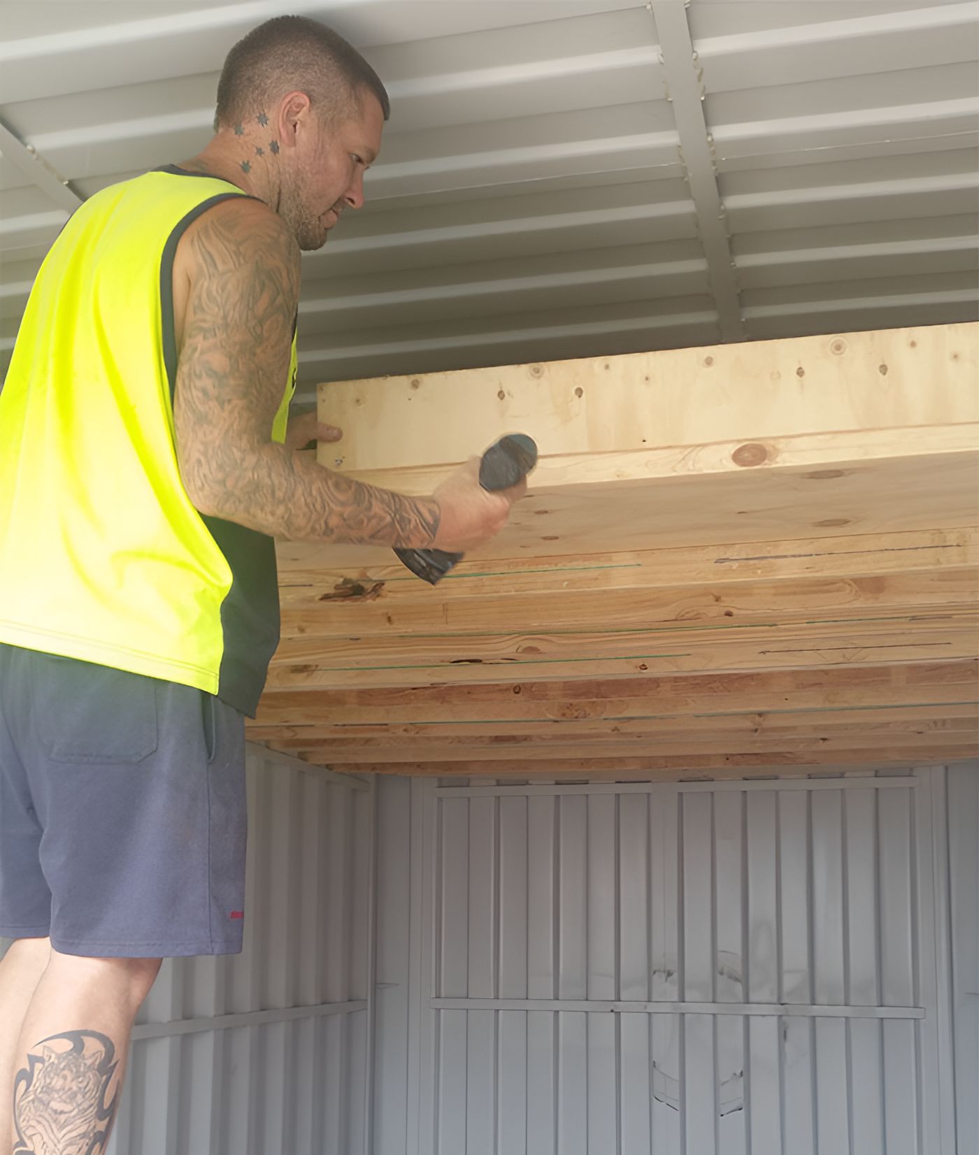 A Man In A Yellow Vest Is Working On A Wooden Ceiling — Port Stephens Removals & Storage In Medowie, NSW