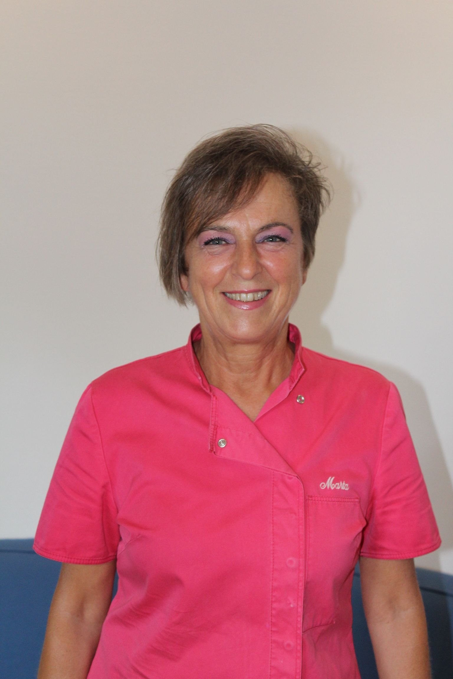 Una donna con una maglietta rosa sorride alla telecamera.