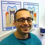Un uomo con gli occhiali sorride in uno studio dentistico