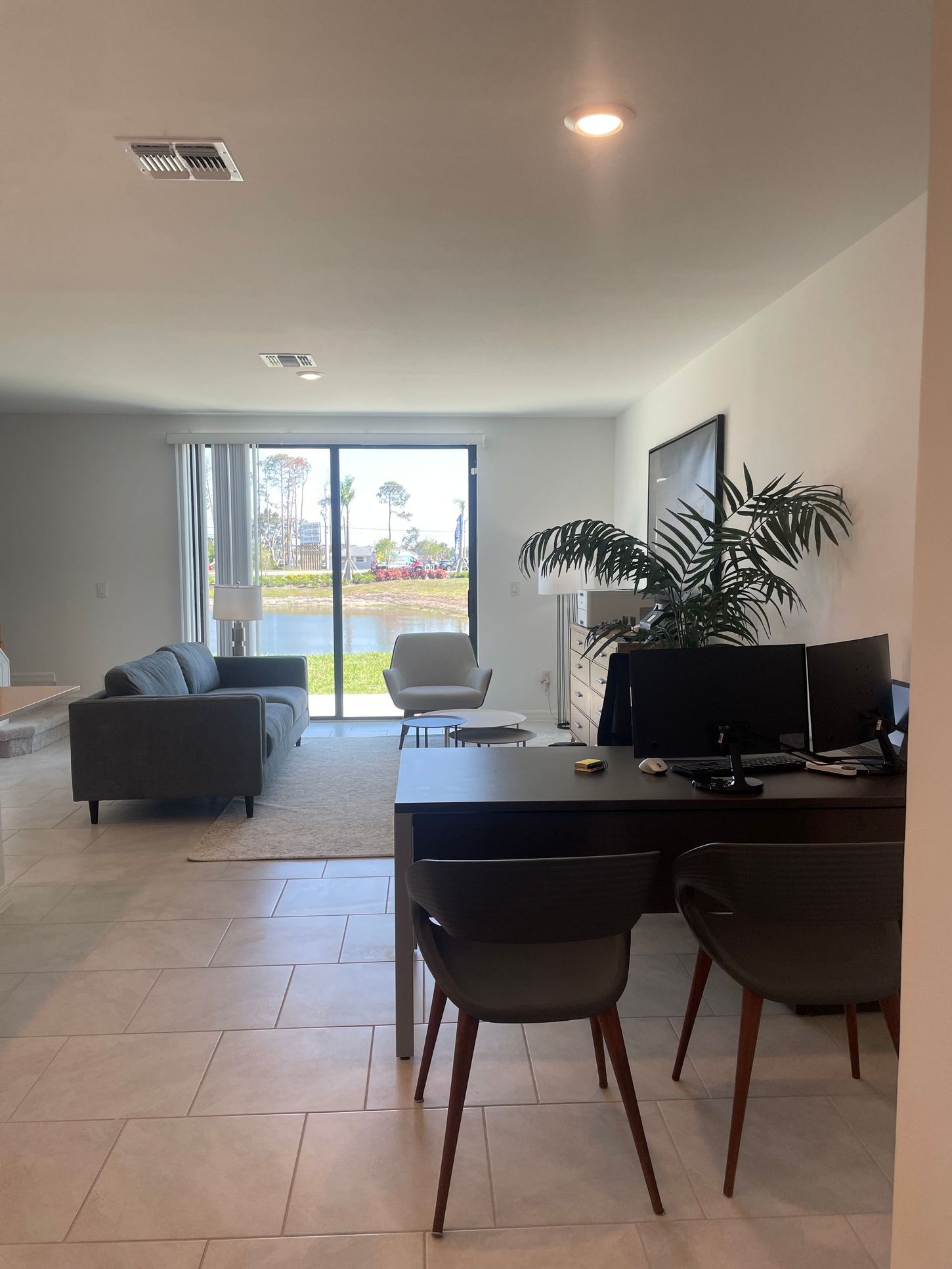 Modern open-plan living room with sofa, dining table, TV, and large sliding glass doors.