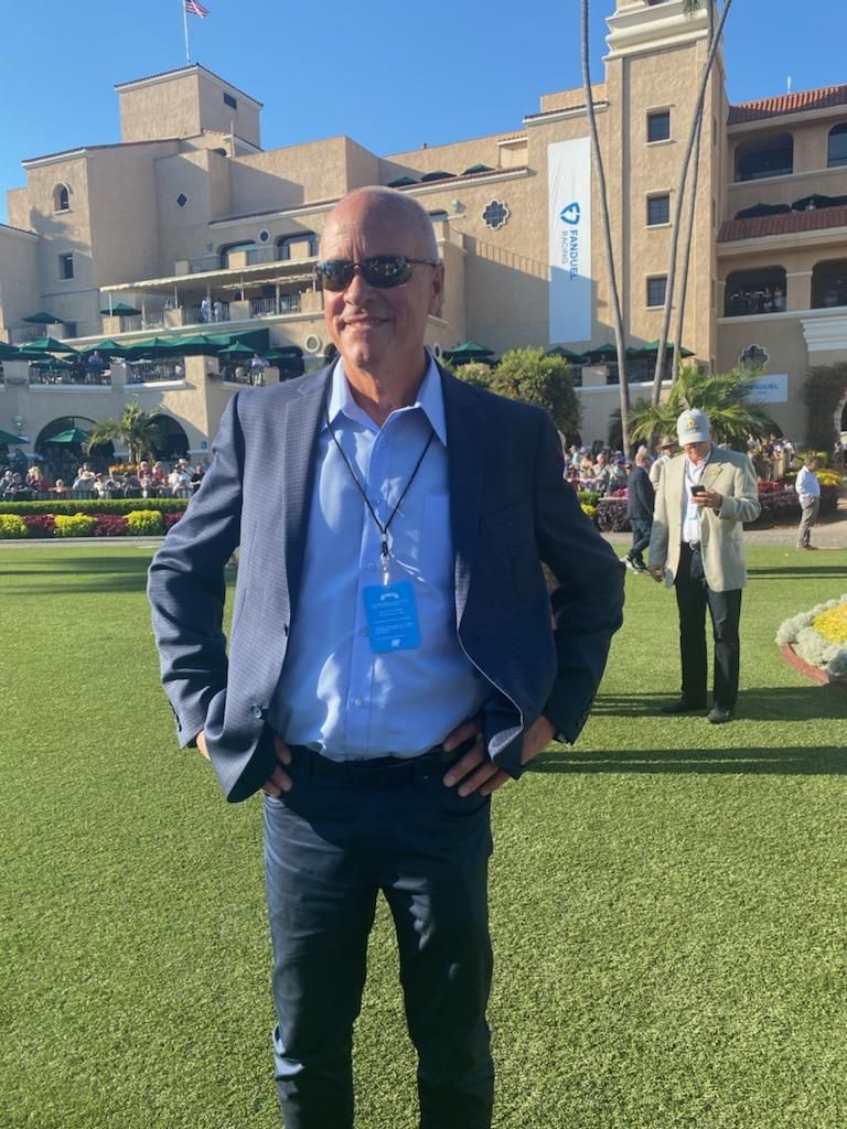 A man in a suit stands in front of a large building