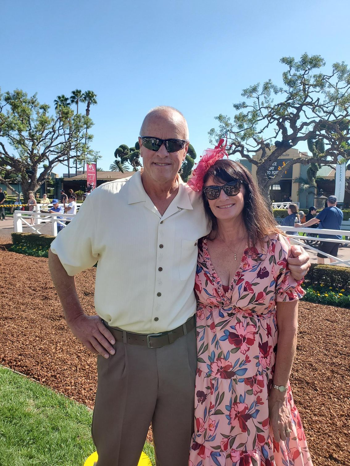 A man and a woman are posing for a picture at a race track.