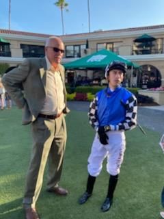 A man in a suit stands next to a jockey