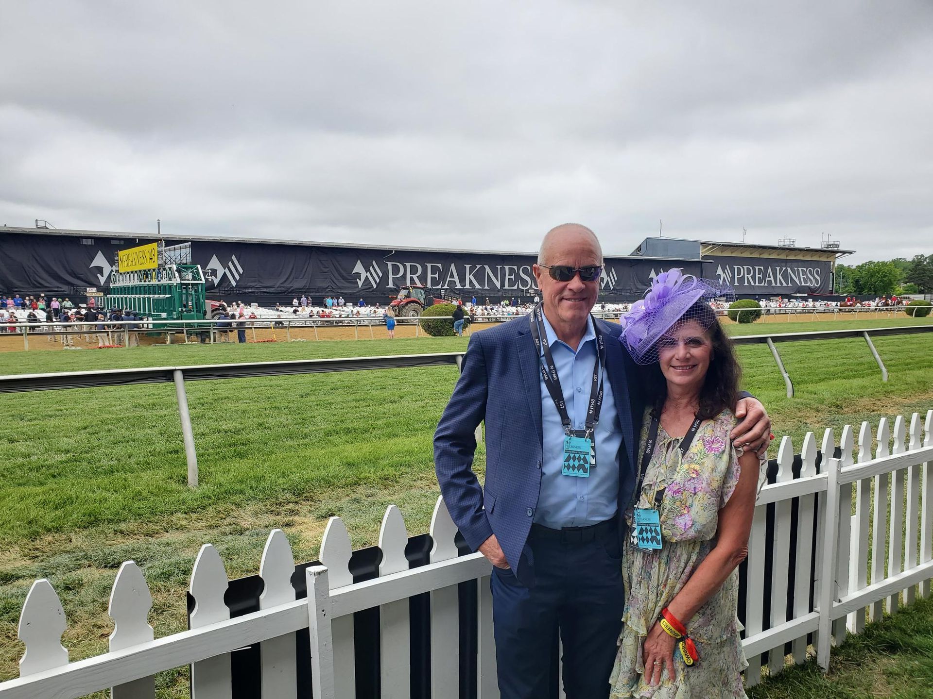 A man and a woman are posing for a picture in front of a white picket fence.