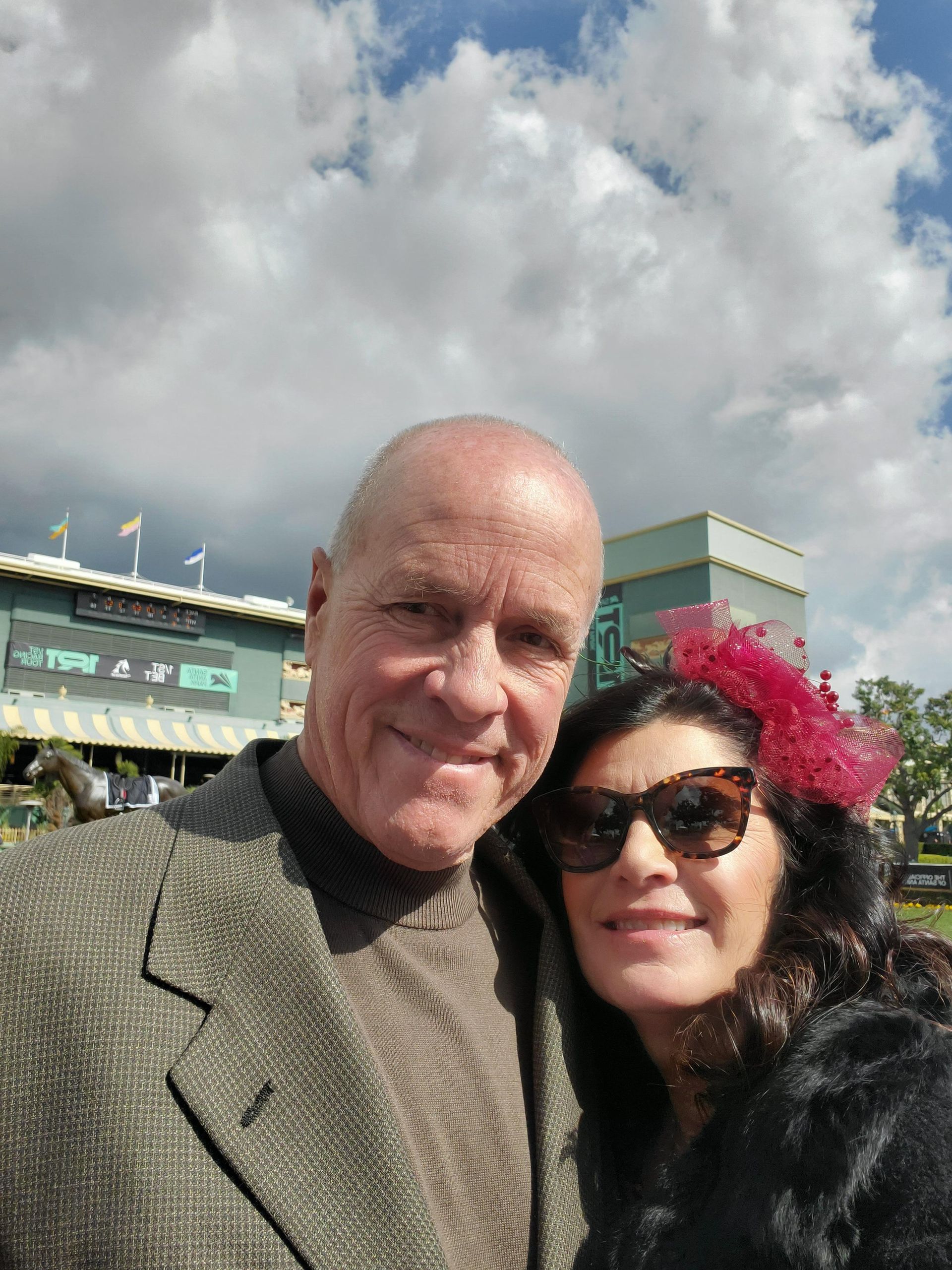 A man and a woman pose for a picture in front of a stadium