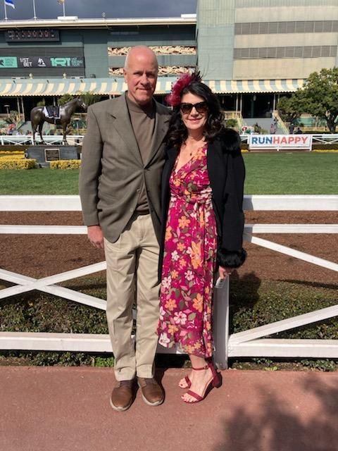 A man and a woman are posing for a picture at a race track.