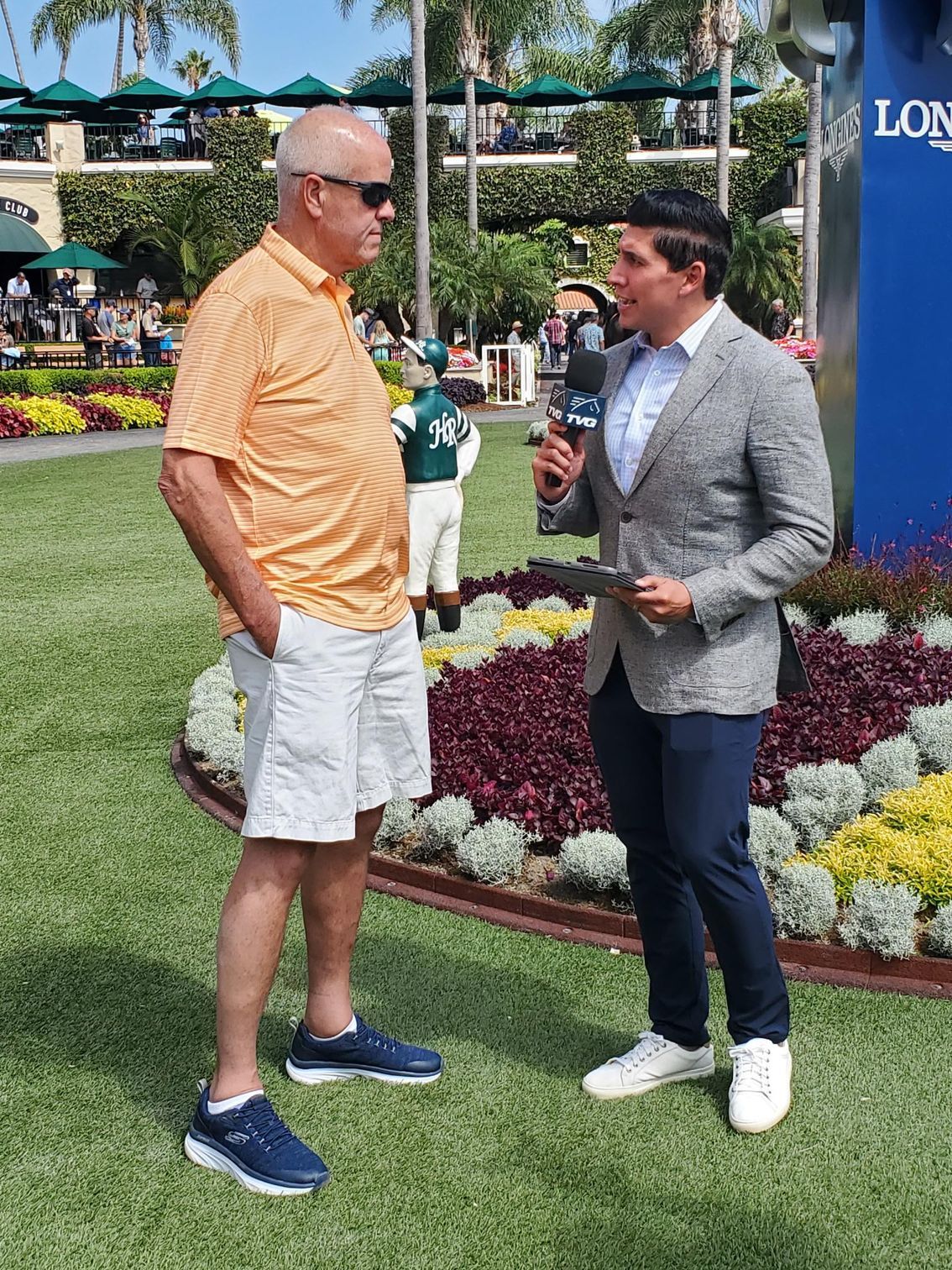 A man is talking to another man while holding a microphone.