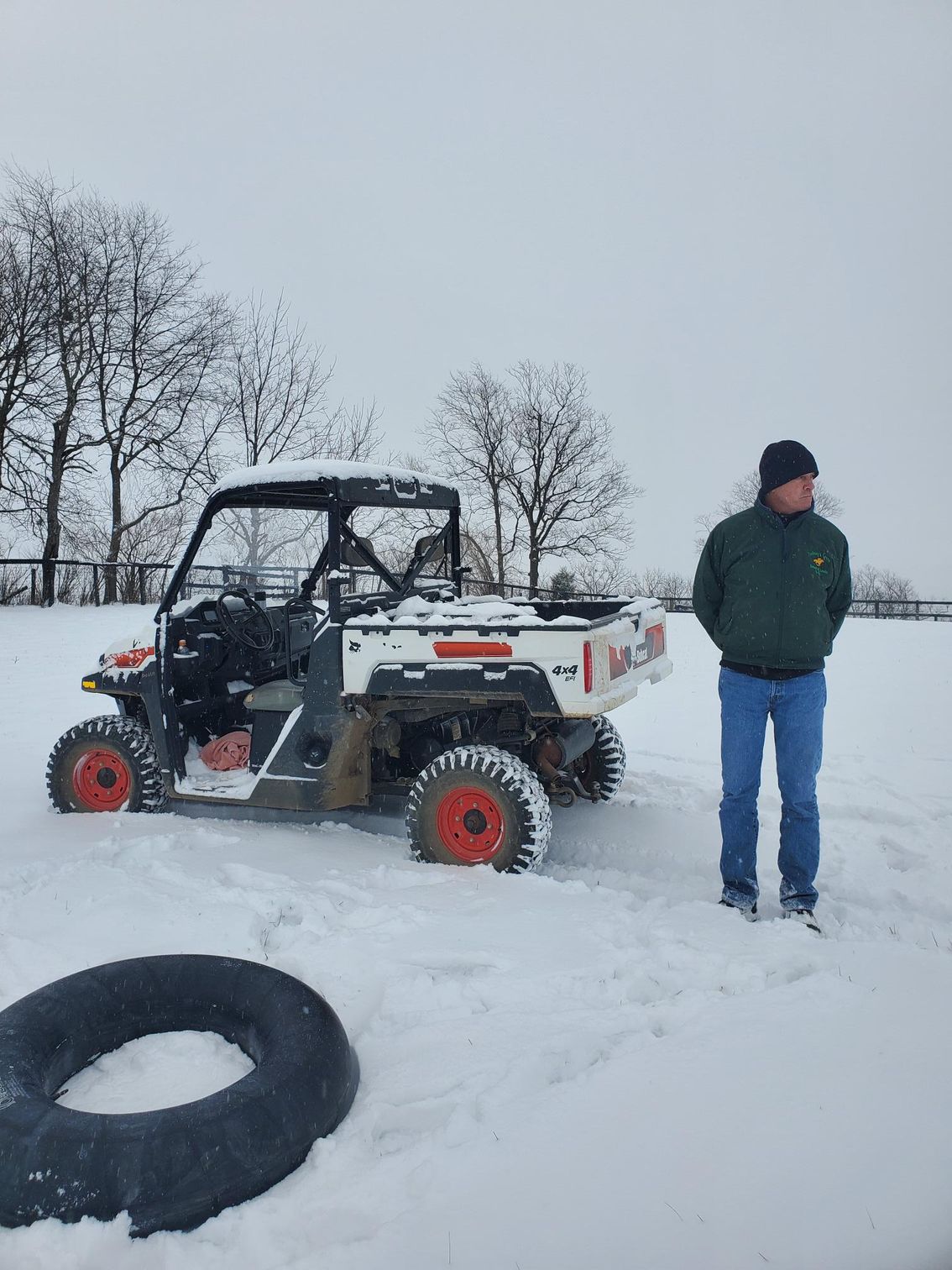 A man is standing next to a atv in the snow.