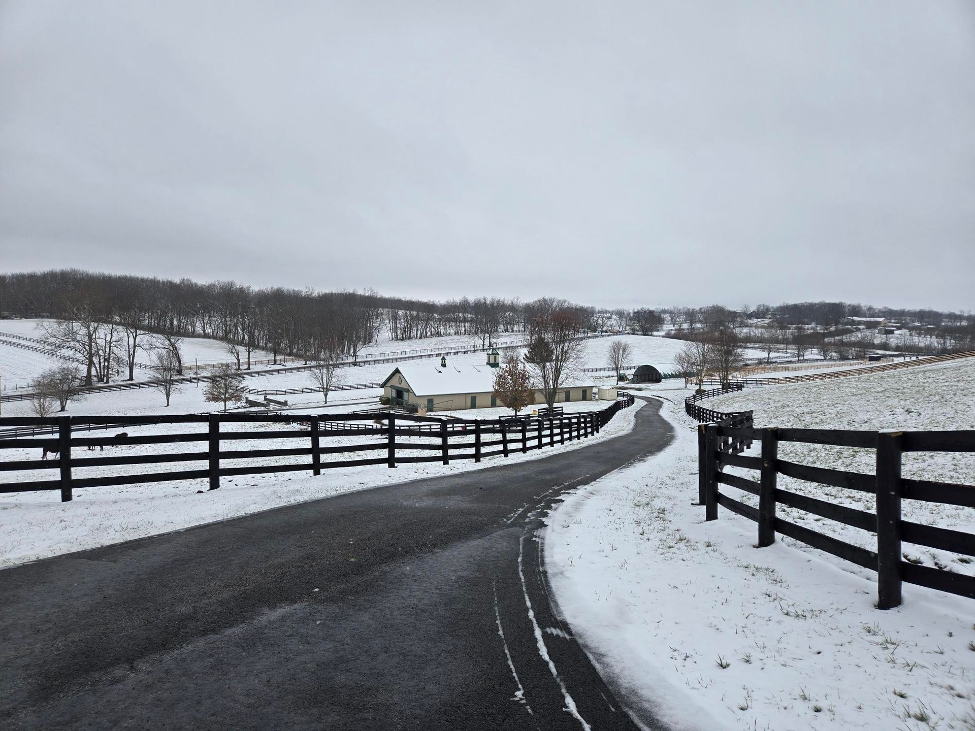 A snowy road with a fence on the side of it