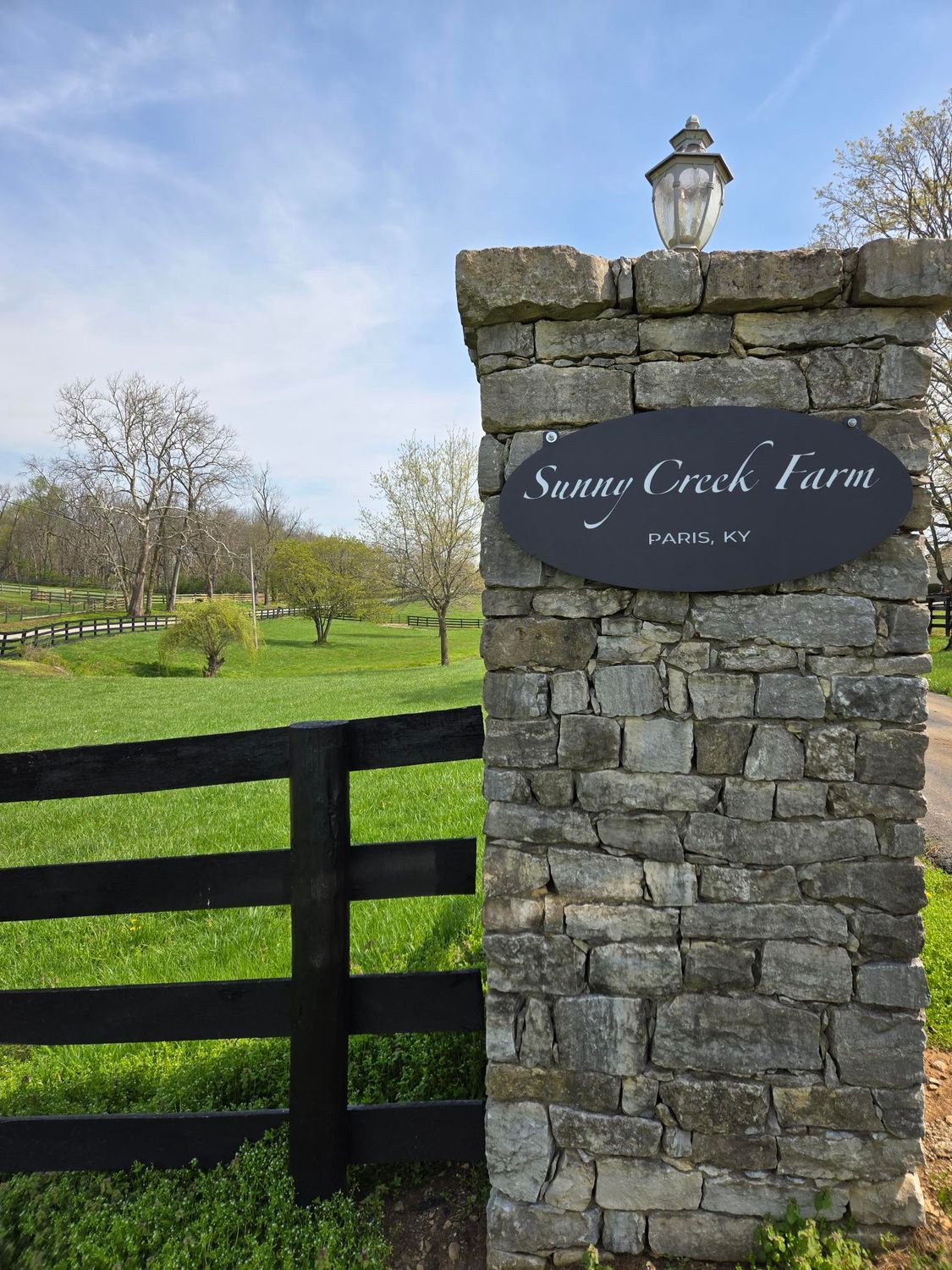 A stone wall with a sign that says savage creek farm