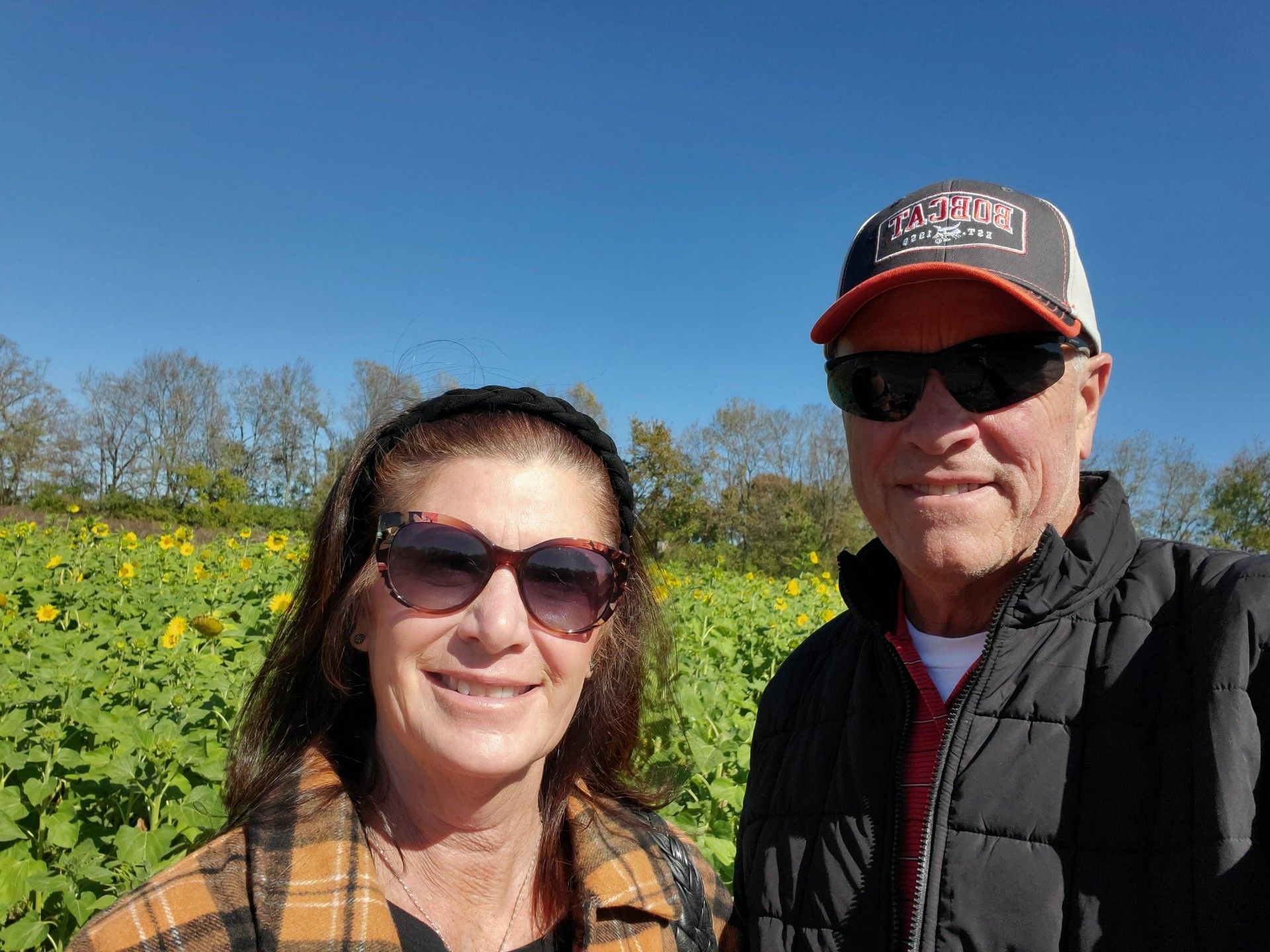 A man and a woman are standing in a field of sunflowers.