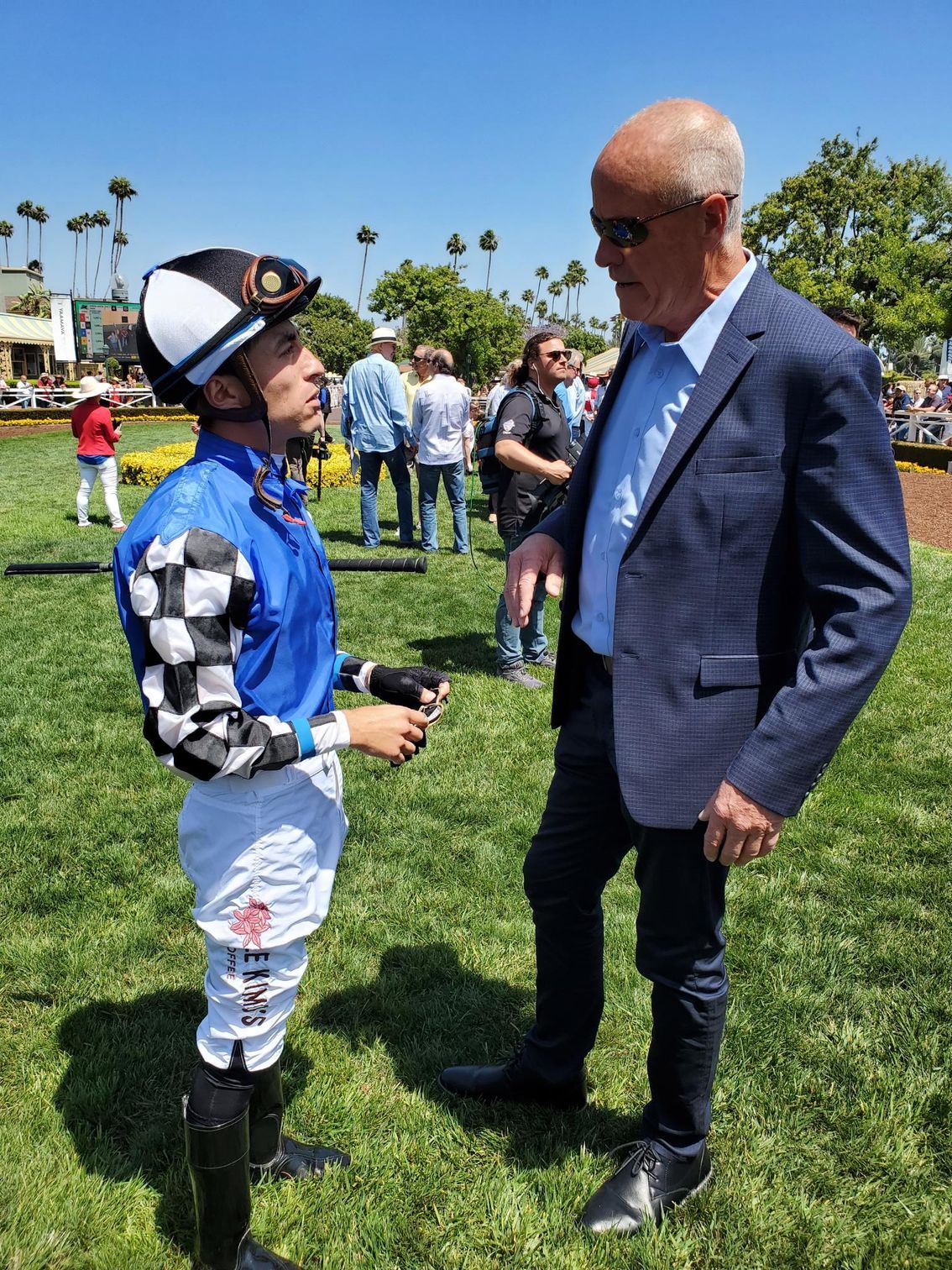 A jockey is talking to a man in a suit