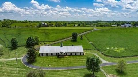 An aerial view of a large house in the middle of a lush green field.