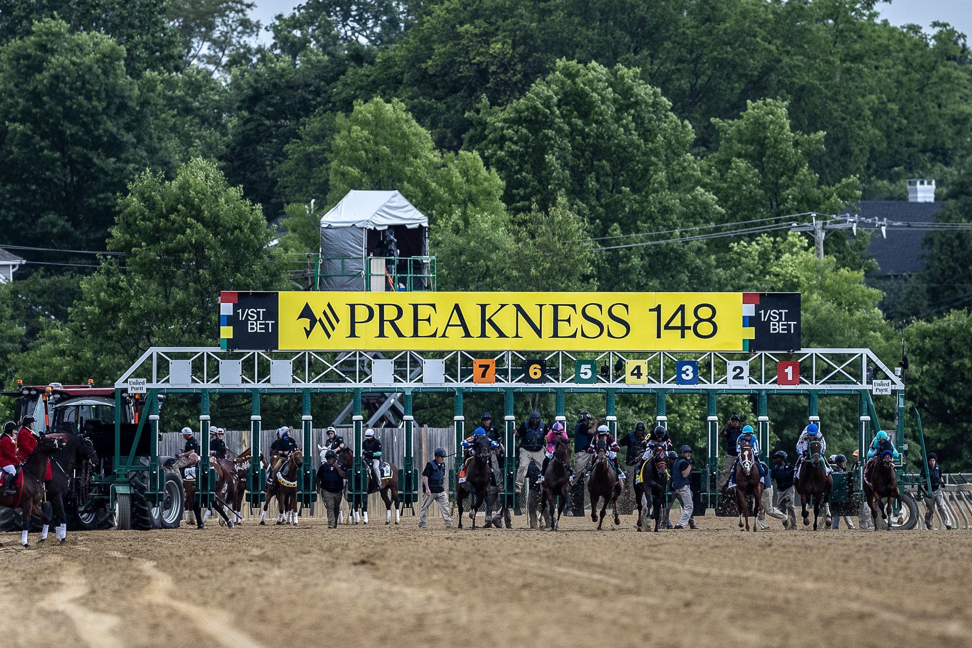 A group of horses are standing in front of a sign that says preakness 148.