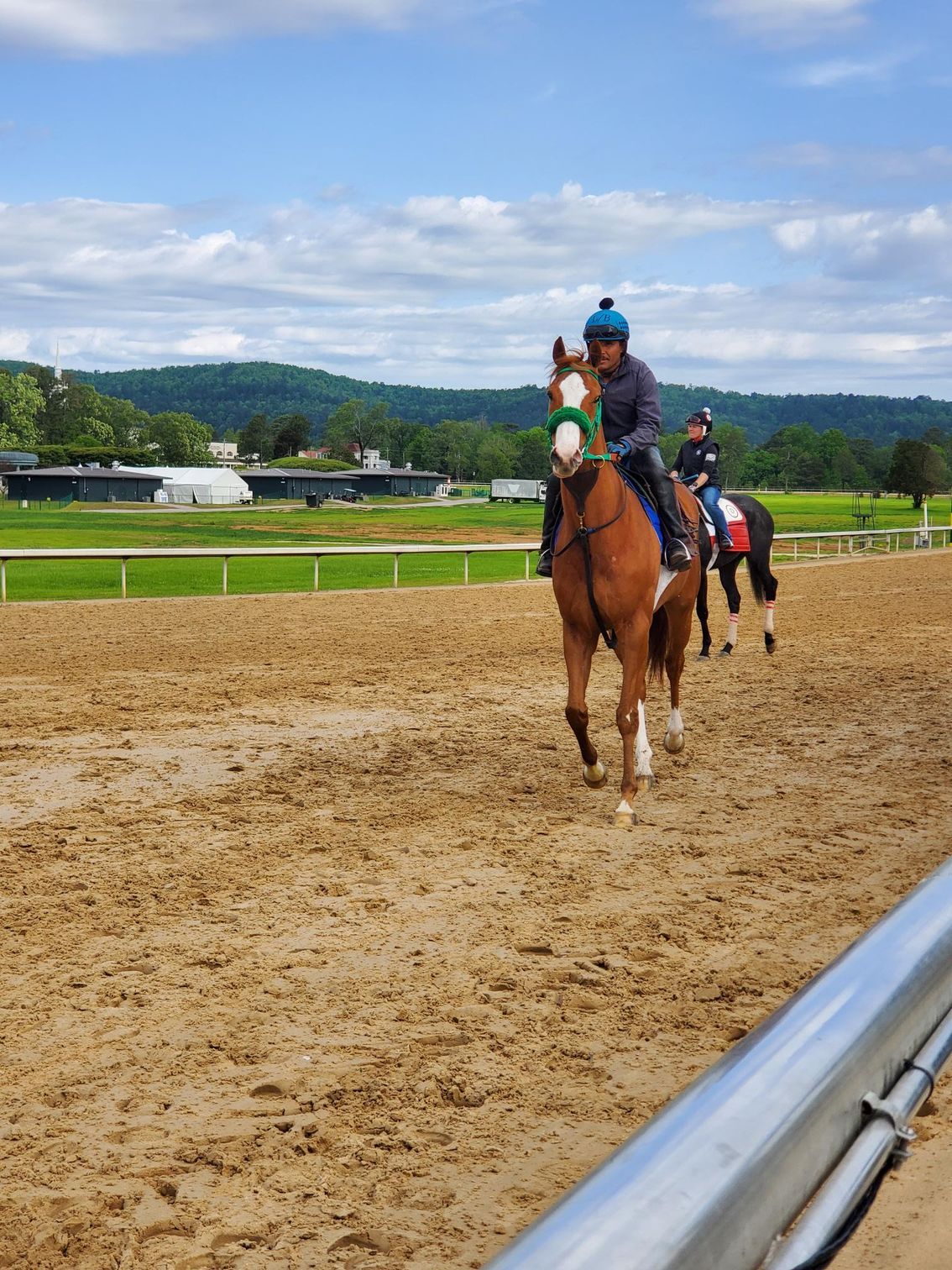 Two people are riding horses on a dirt track