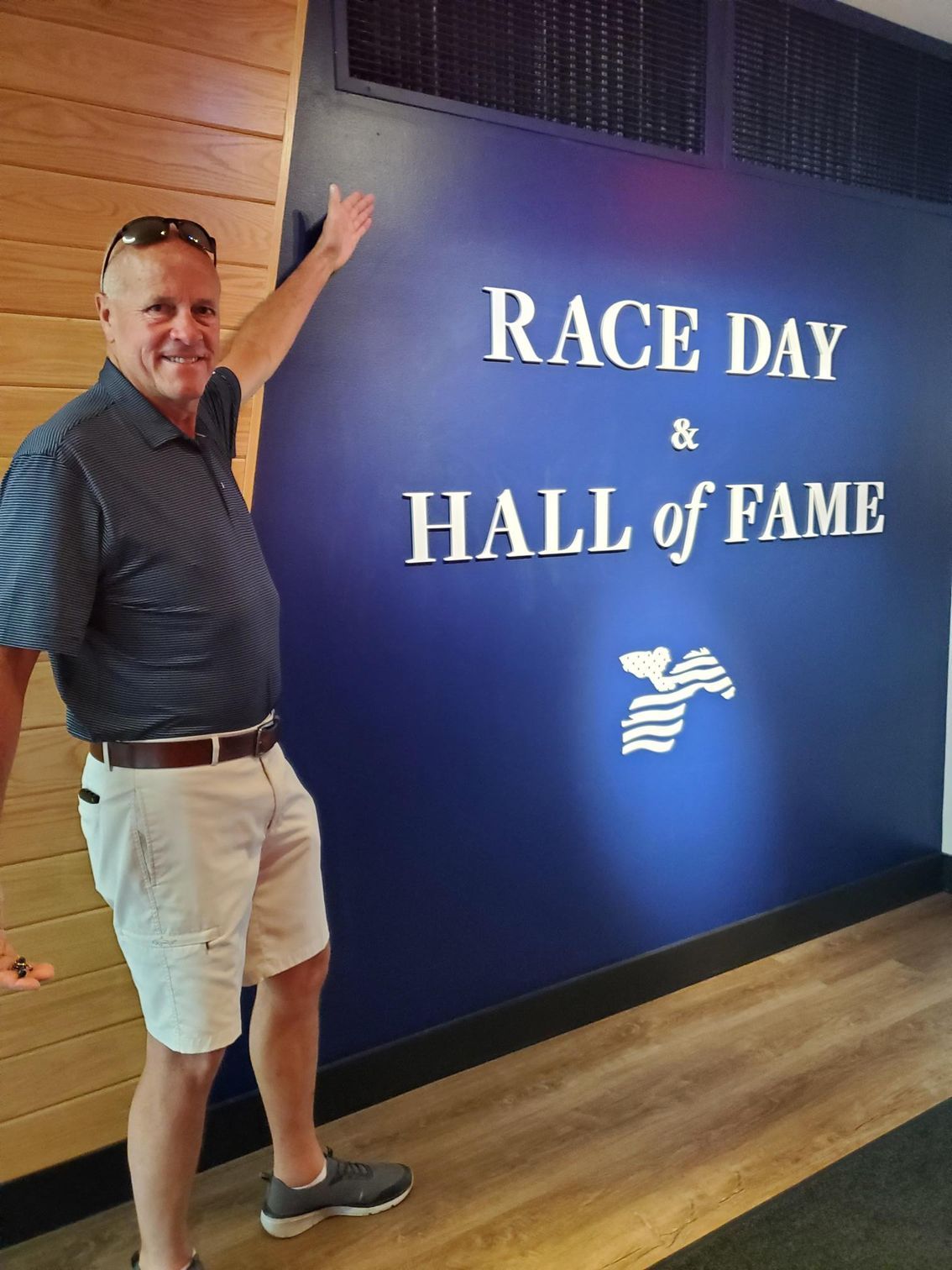 A man standing in front of a wall that says race day hall of fame