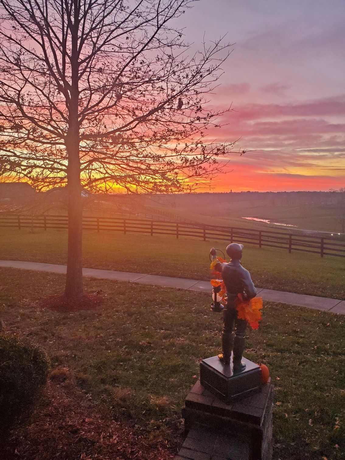 A statue of a man standing on a pedestal in front of a sunset.