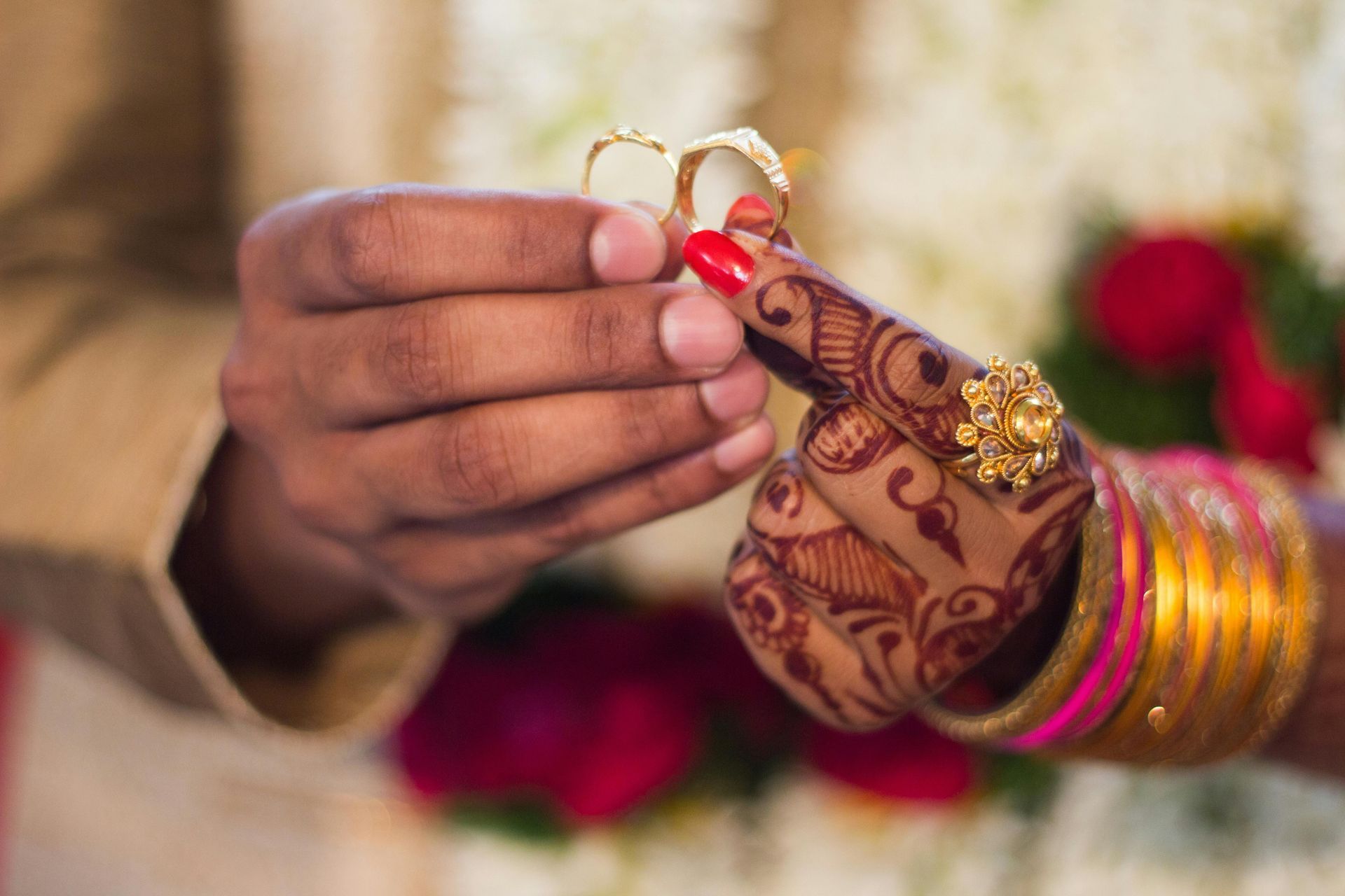 A bride and groom are putting wedding rings on each other 's finger.