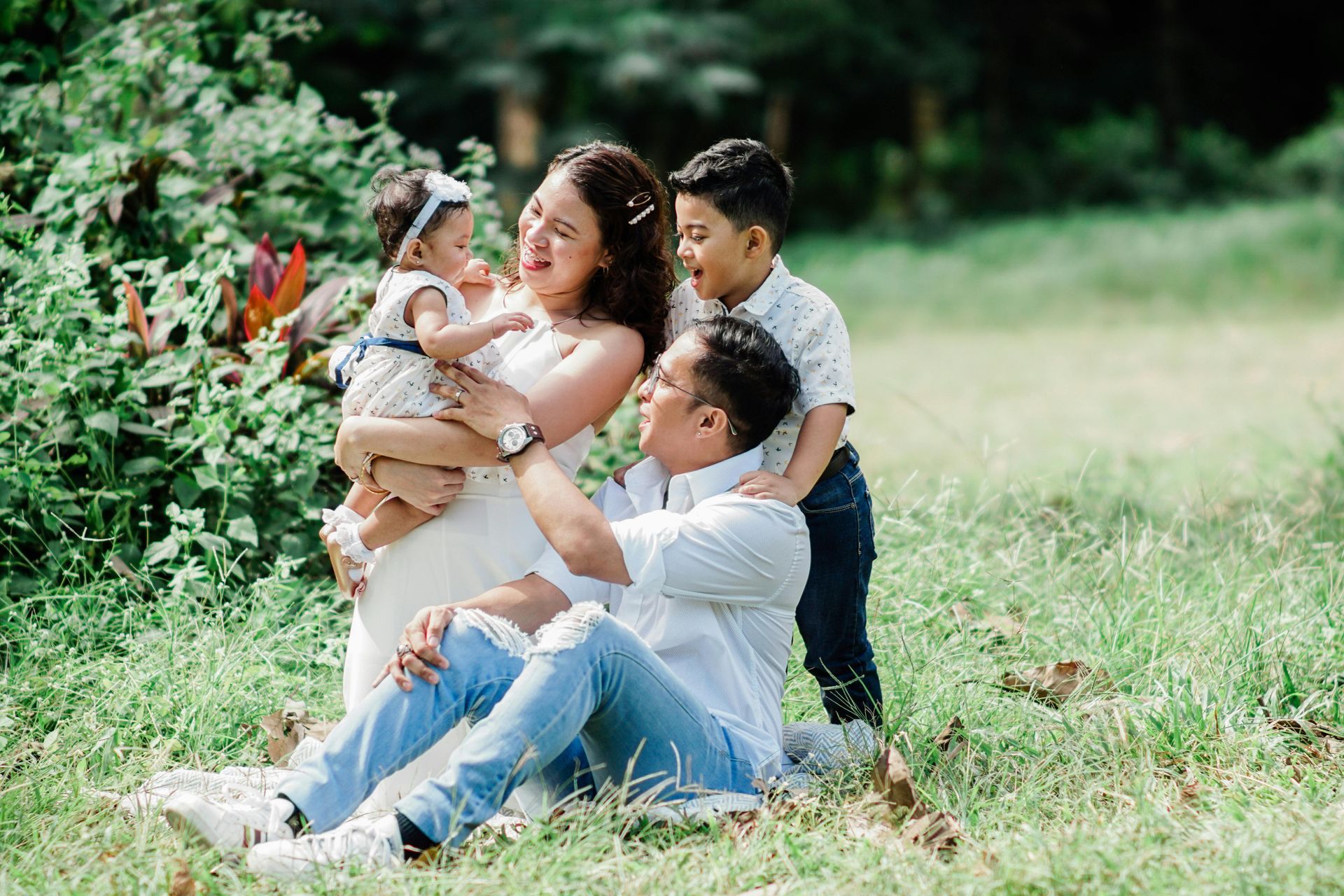 A family is sitting on the grass in a park.