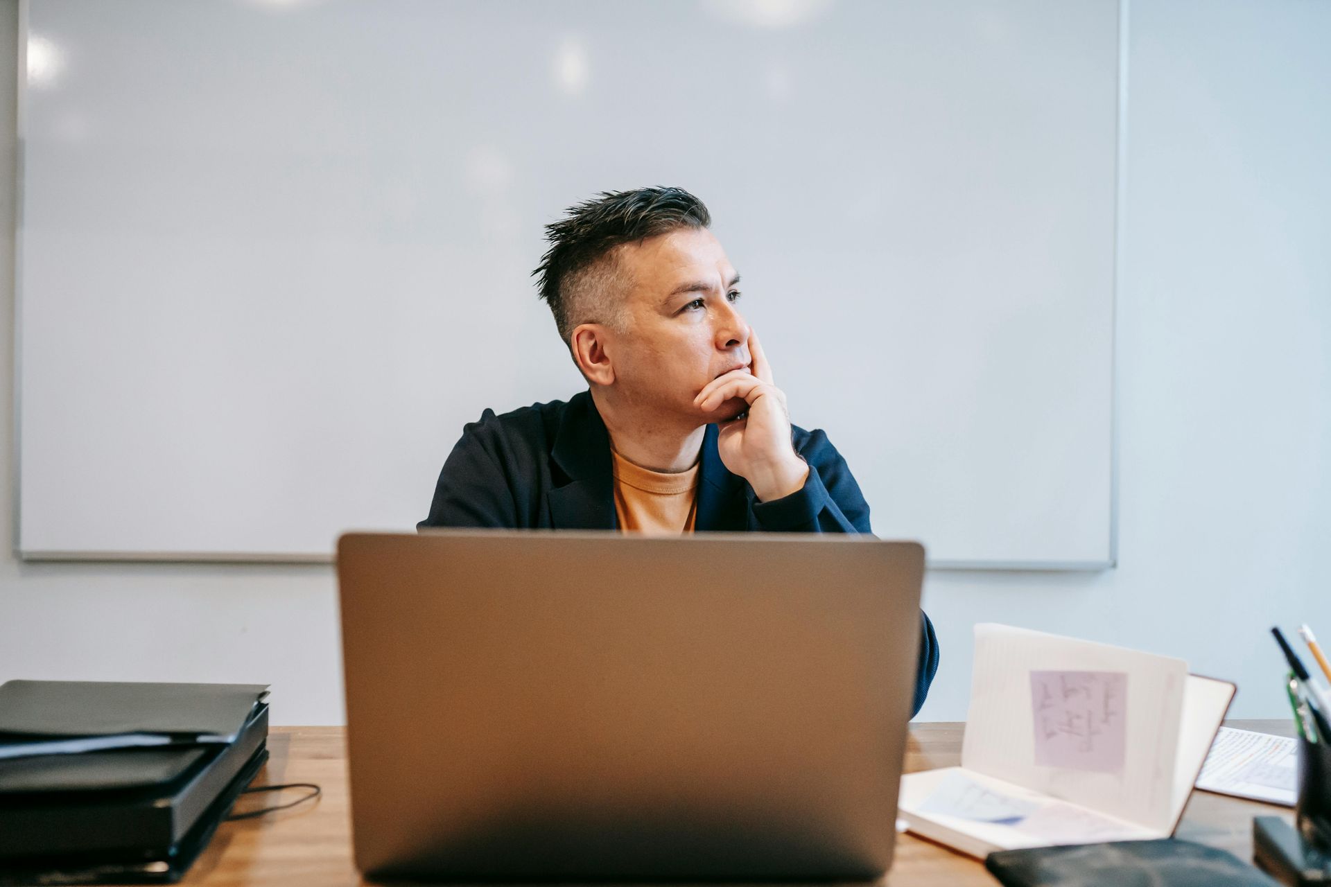 man sitting in front of laptop looking out window