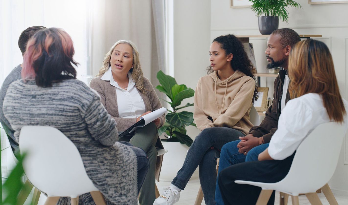 A group of people are sitting in a circle talking to each other.