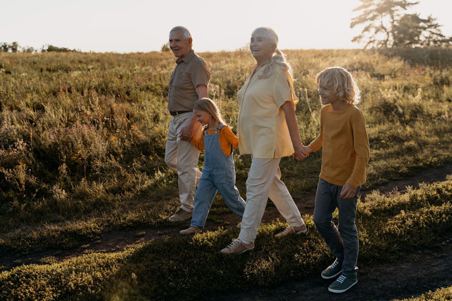 A family is walking through a field holding hands.