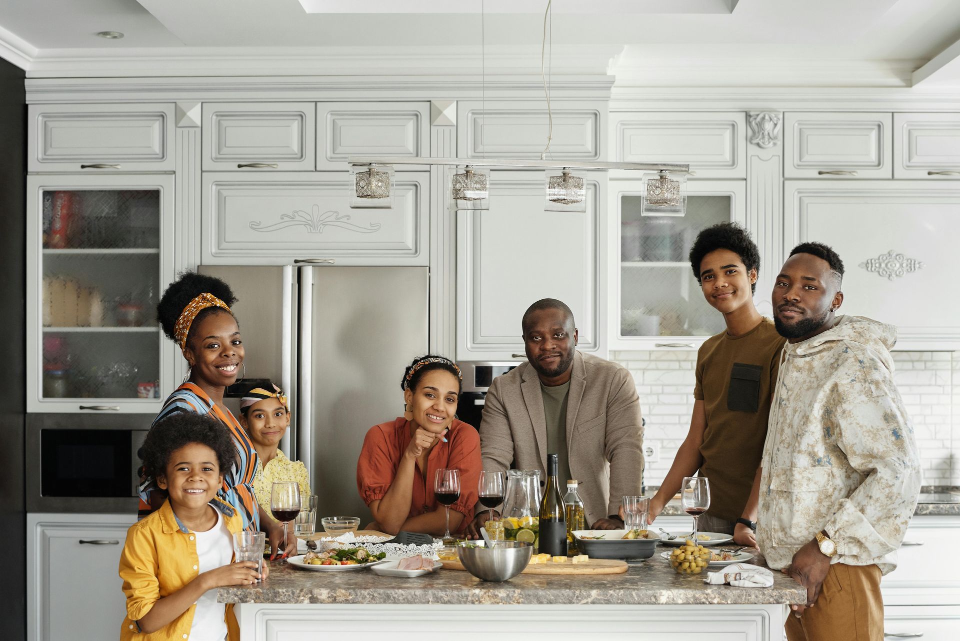 A large family is sitting at a table in a kitchen.