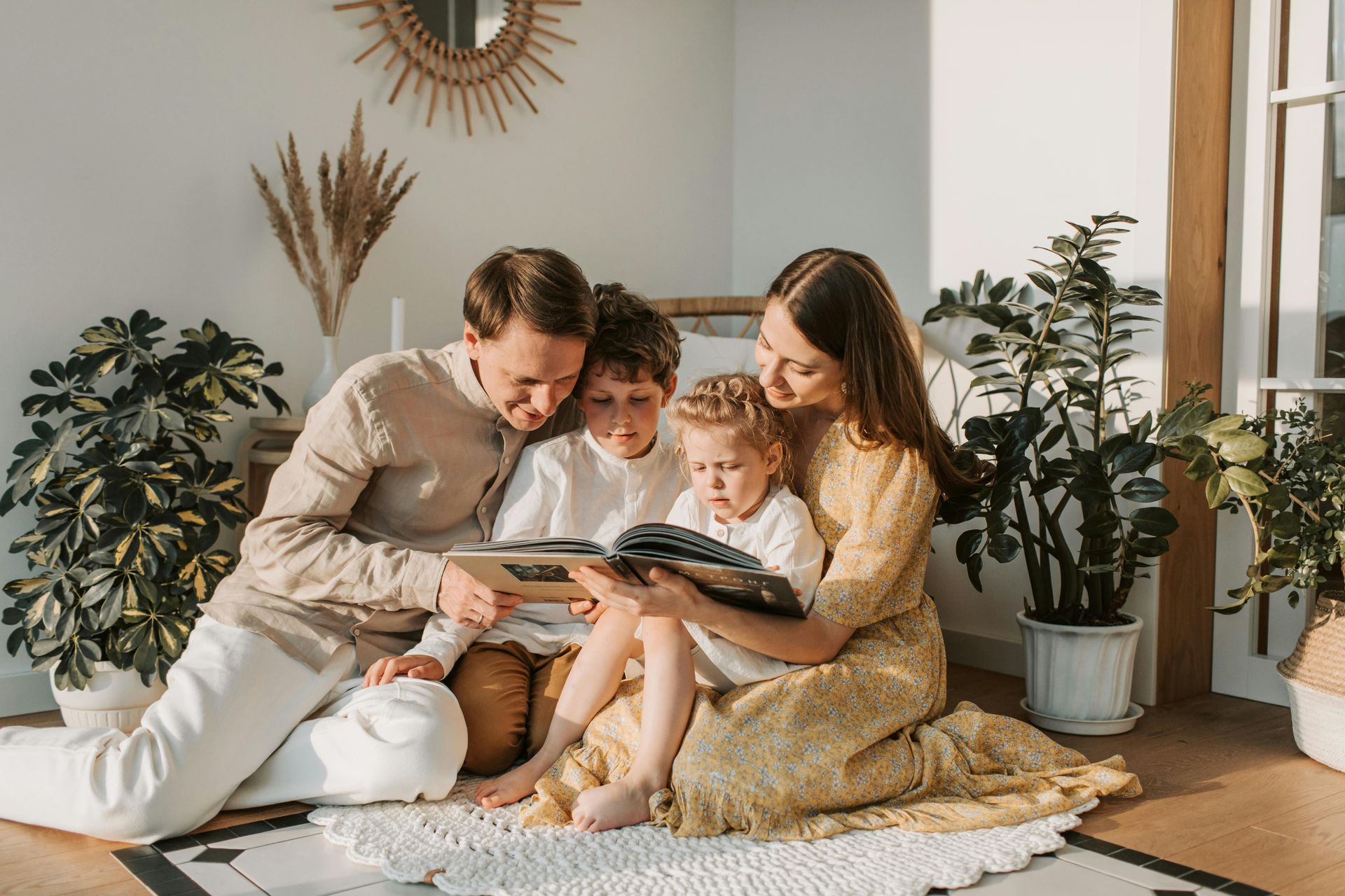A family is sitting on the floor reading a book together.