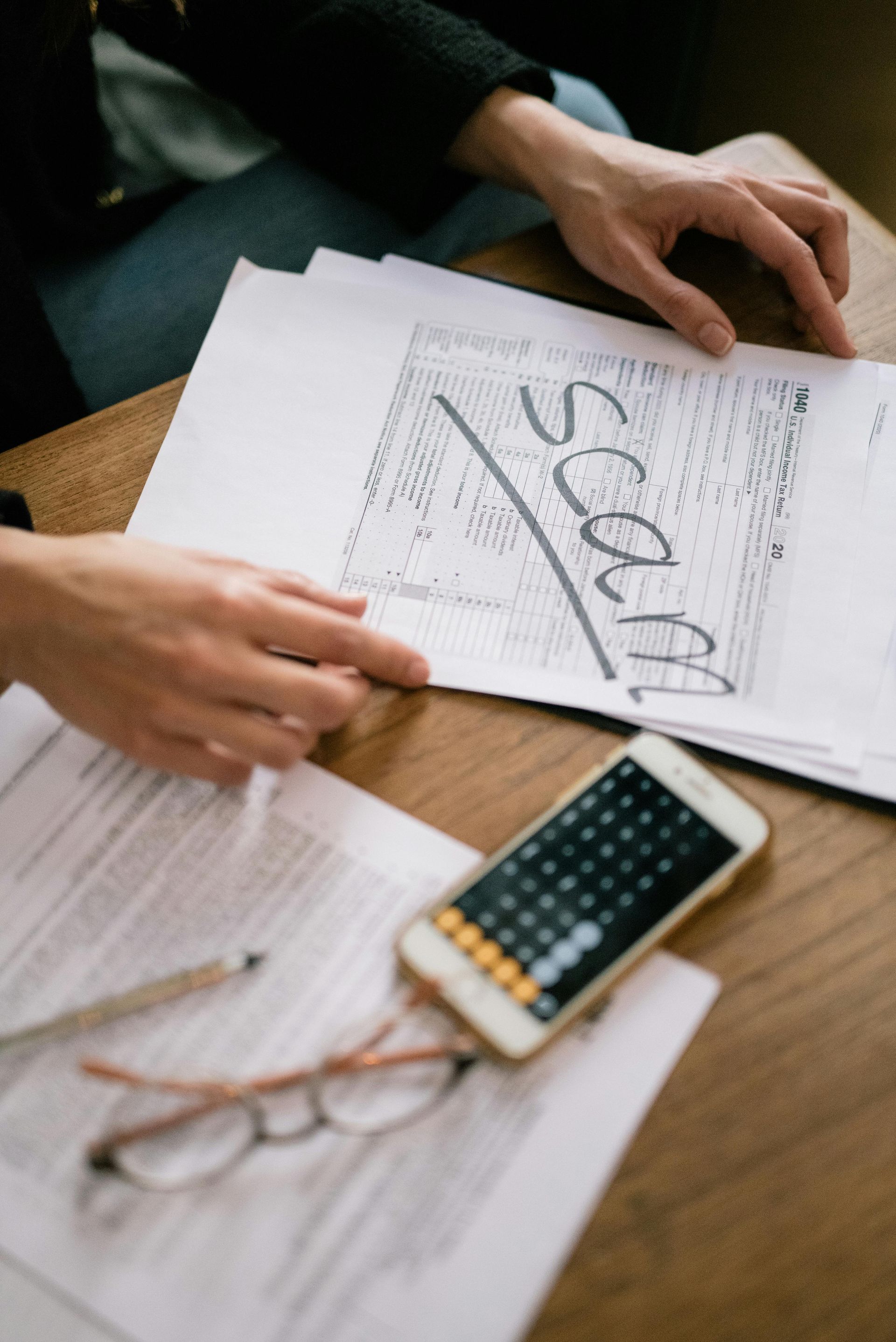 A person is sitting at a table with papers and a cell phone.