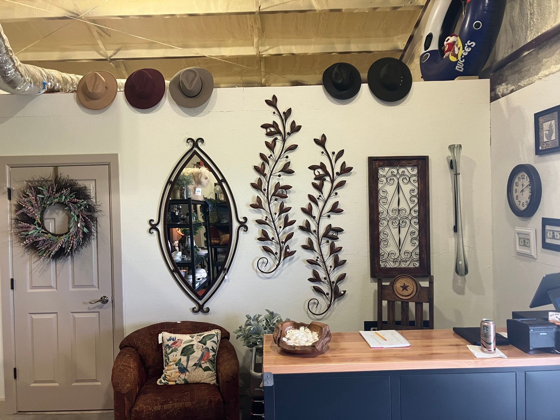 Interior shop with hats, mirror, metal art, and a counter.