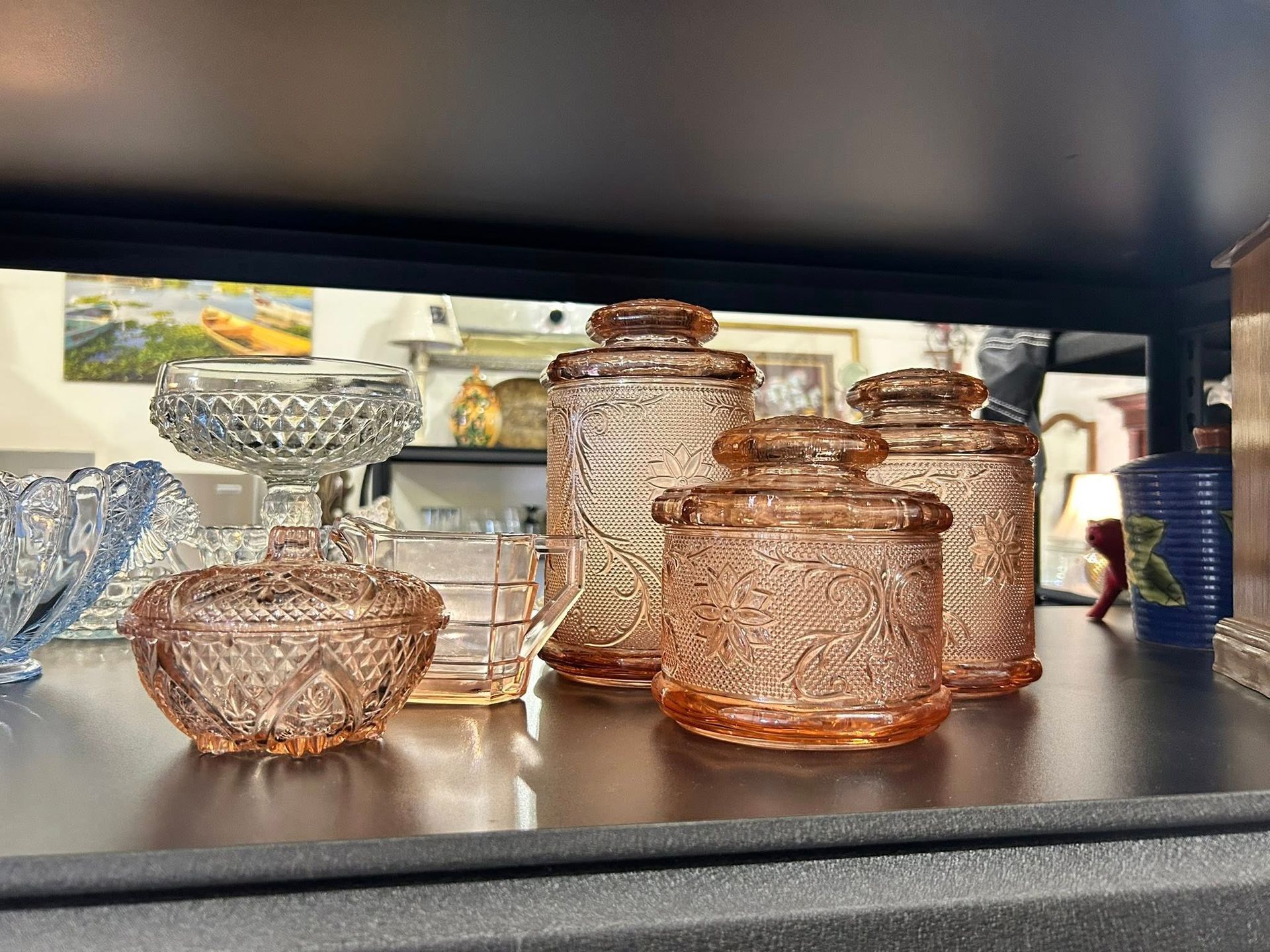 Pink glass jars and dishes on a shelf.