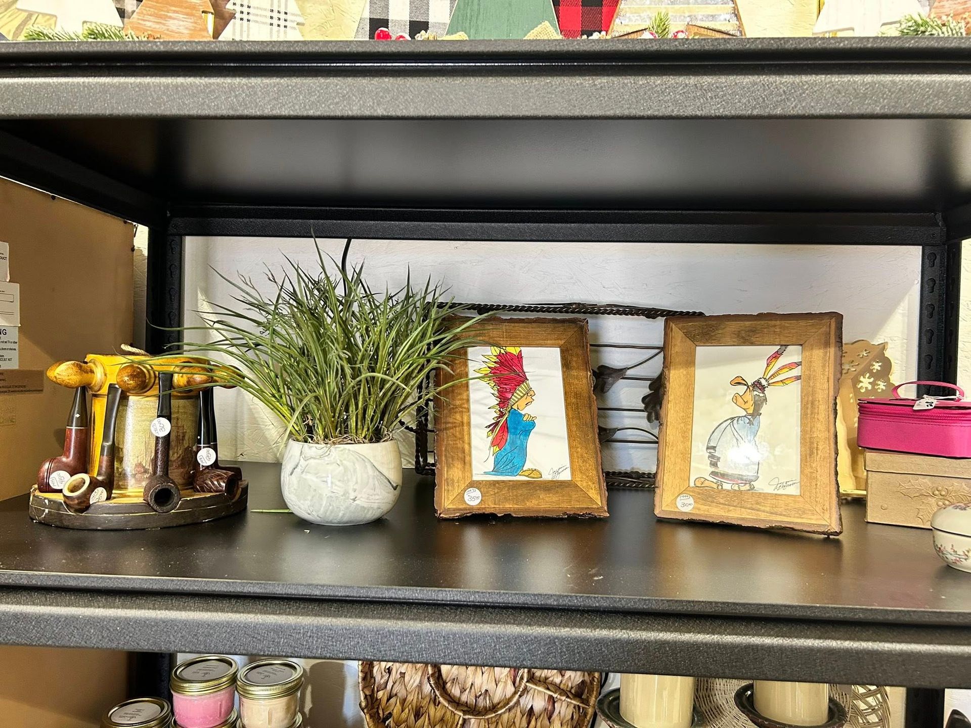 Shelf with decorative items: small framed artwork, plant, and a decorative box.