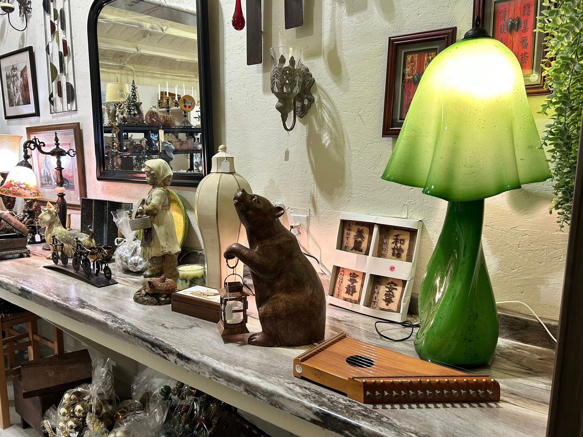 Shelf display: brown bear with lantern, green lamp, antique decor.
