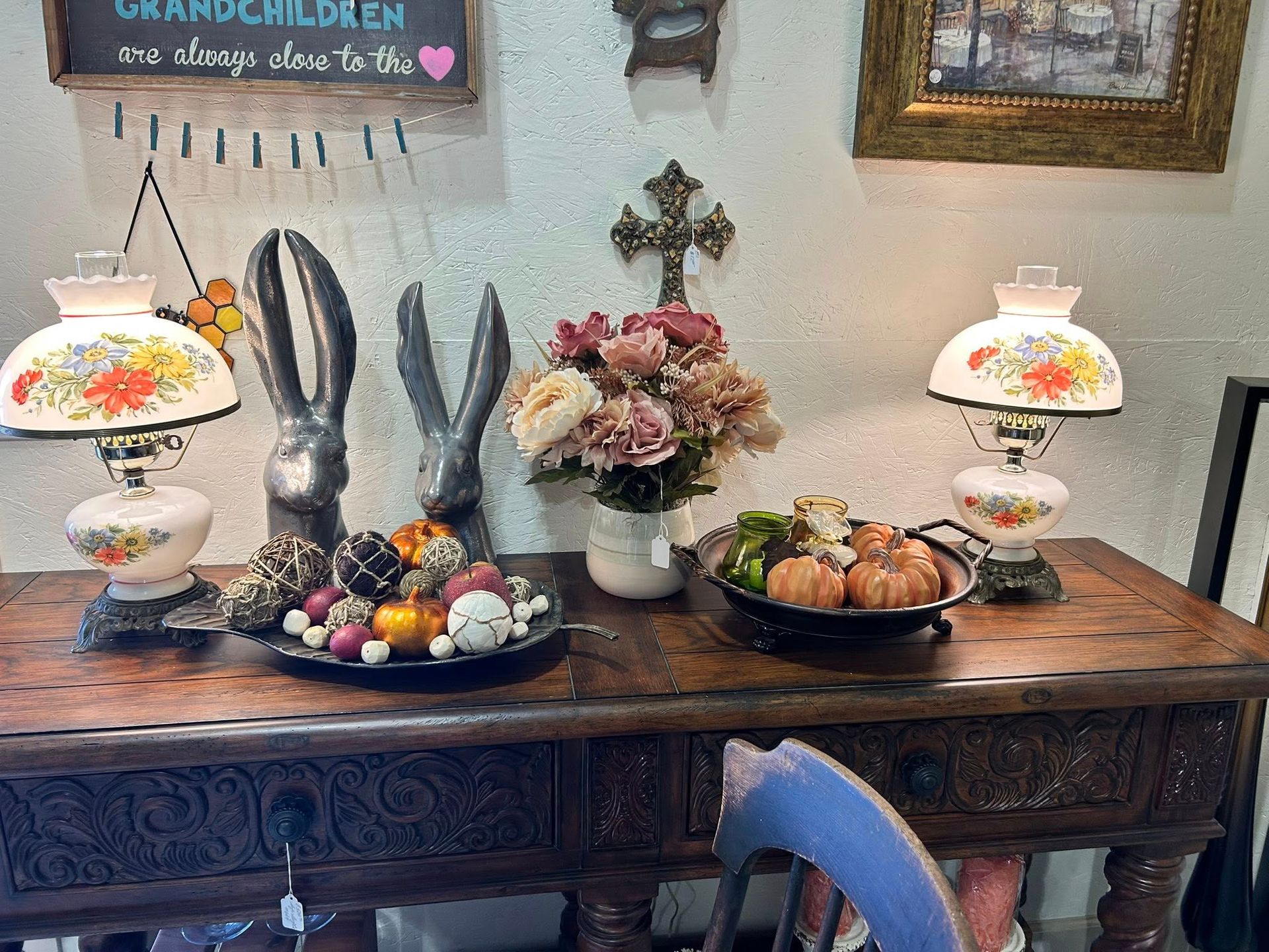 Table with lamps, decorations: floral arrangement, pumpkins, rabbit figures.
