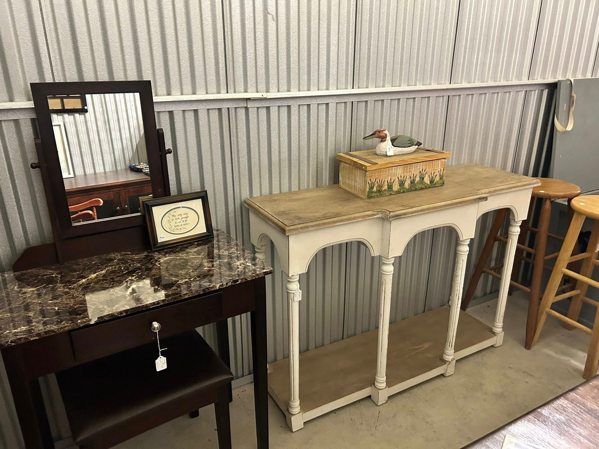 Vanity table with mirror, framed art, and a decorative console table with a wooden duck.