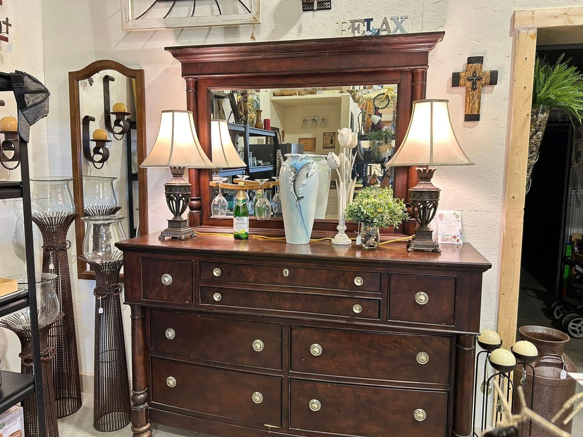 A wooden dresser with a mirror, lamps, and decorative items.