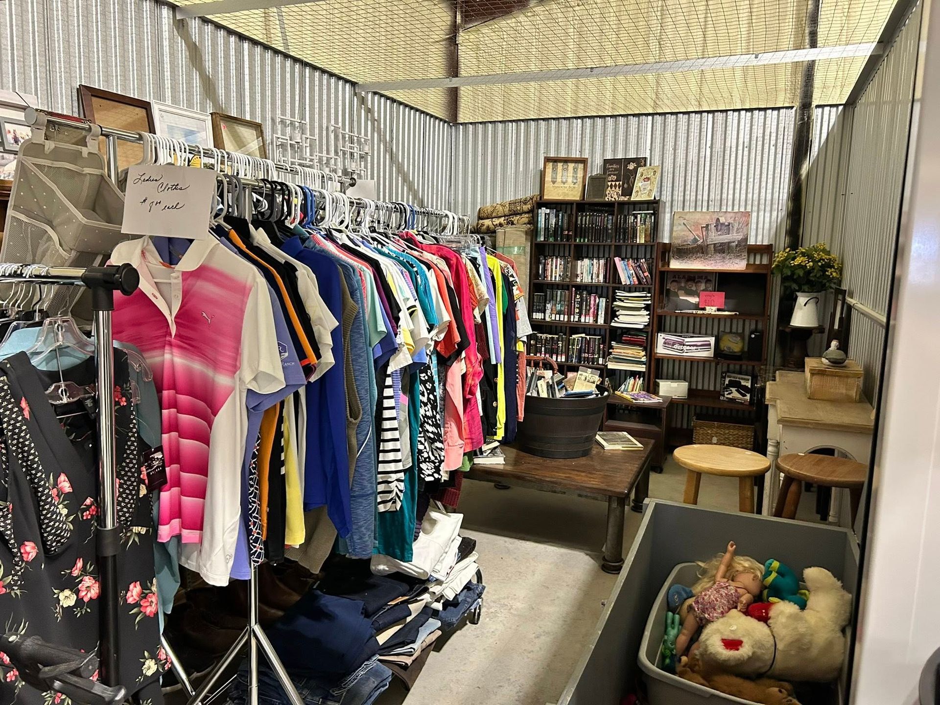 Clothes rack and shelves in a storage unit. Various items, including clothing and collectibles.