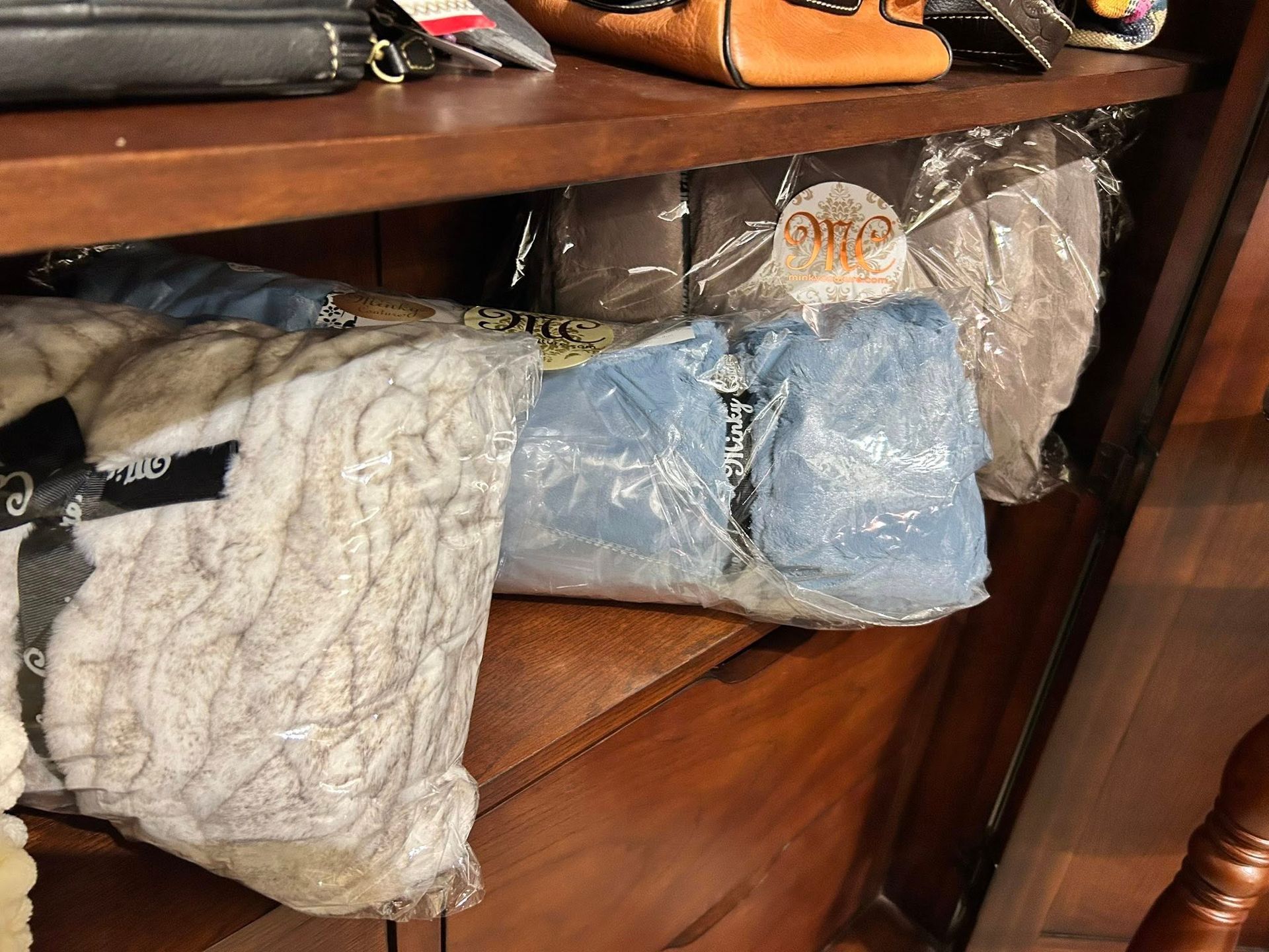 Shelves holding wrapped clothing items in plastic, including a blue garment and a light-colored sweater.