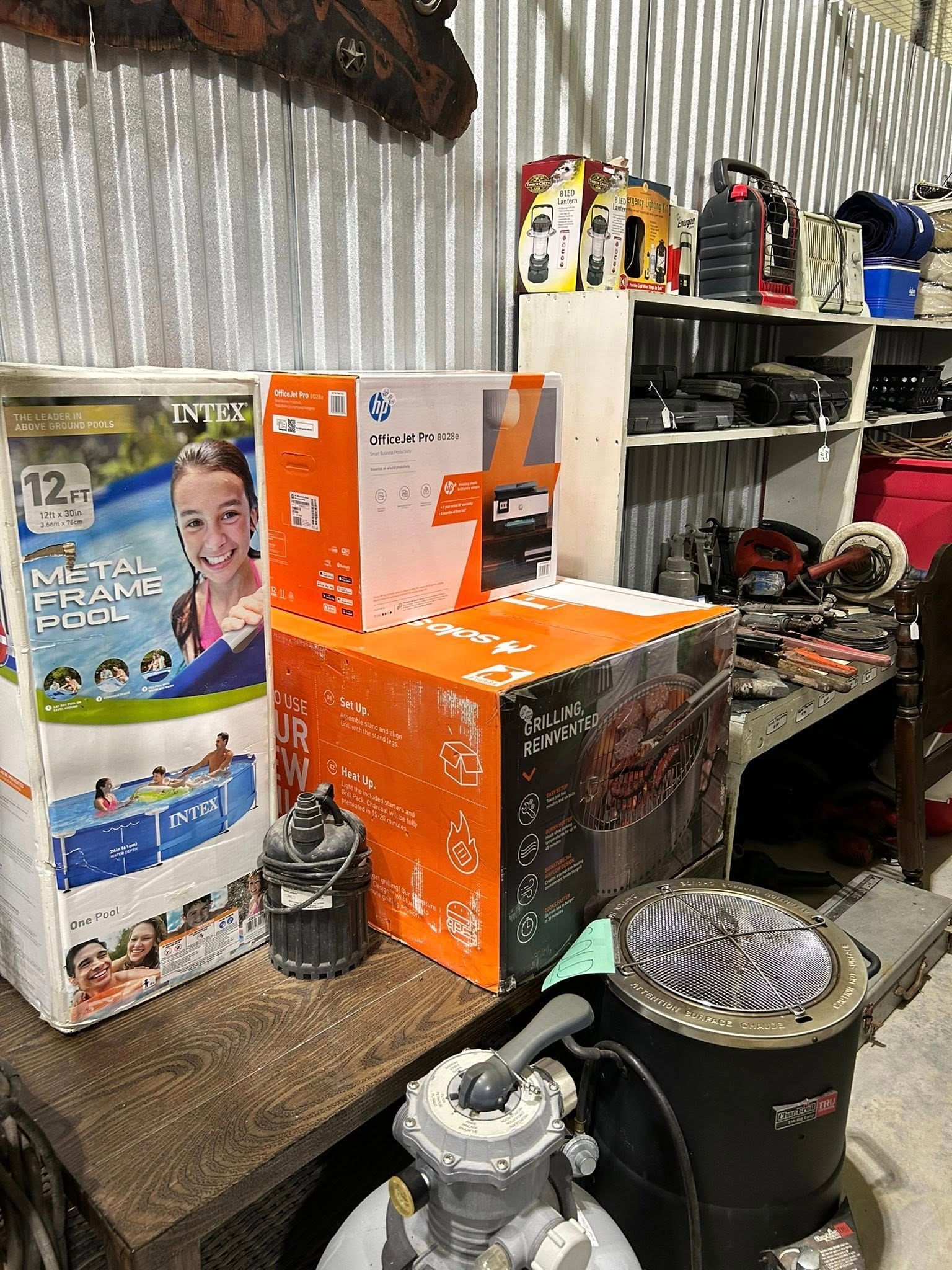 Boxes of merchandise on a shelf, including a pool and a grill. Various items on shelves in background.