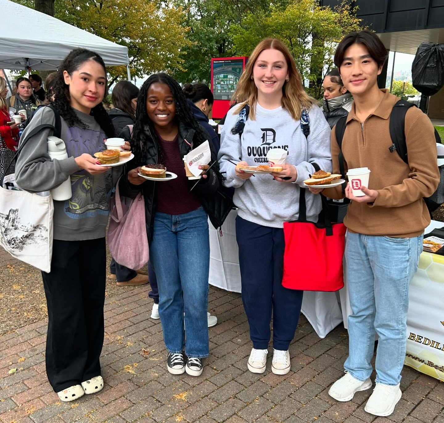 4 Students holding cups of tea and bread with jam.