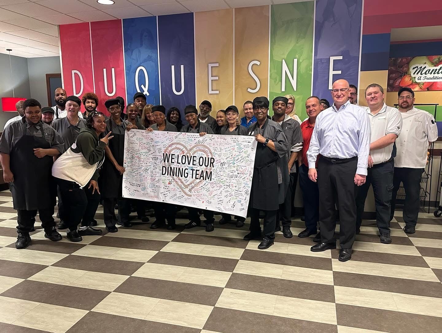 A group of team members are posing for a picture with a 