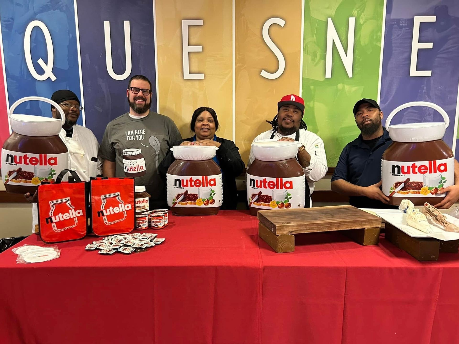Five team members posing for a photo in front of a table with Nutella merchandise. 