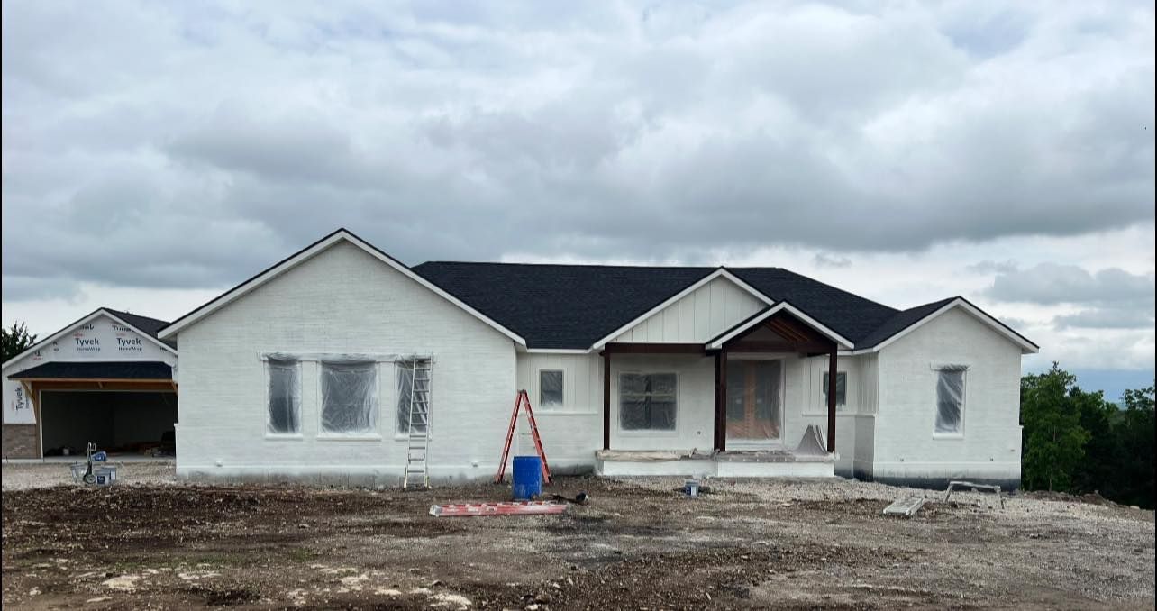White house under construction, dark roof, cloudy sky, construction materials visible.