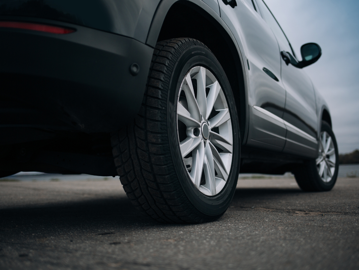Black SUV, rear quarter view, parked on a gray surface with the ocean and sky in the background.