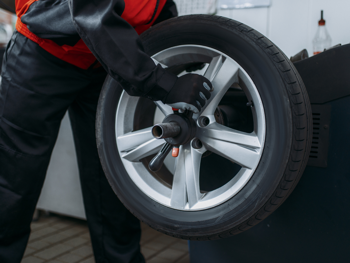 Mechanic balancing a car tire with a machine in a shop.